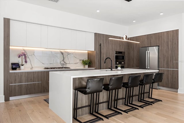 kitchen with light wood-style flooring, a kitchen breakfast bar, modern cabinets, and light countertops