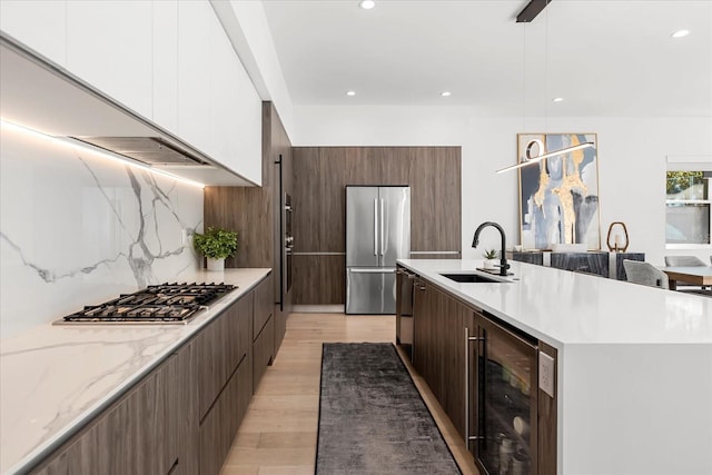 kitchen with beverage cooler, appliances with stainless steel finishes, modern cabinets, and a sink