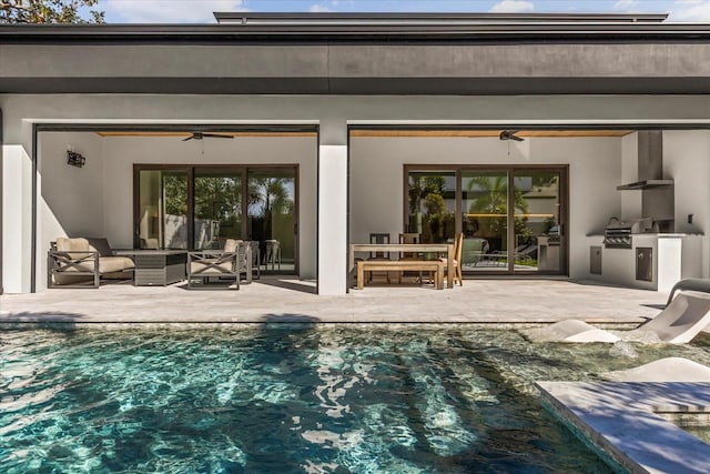 rear view of house with ceiling fan, exterior kitchen, stucco siding, a patio area, and an outdoor pool