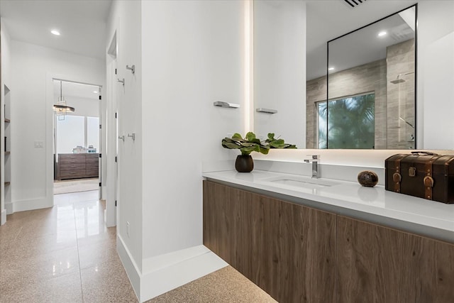 bathroom with recessed lighting, tiled shower, vanity, and baseboards