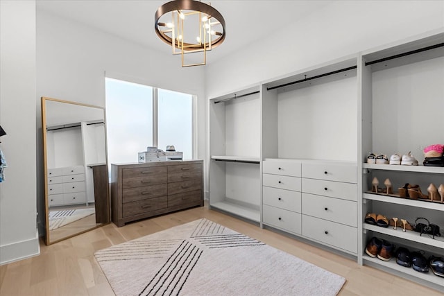 walk in closet featuring a barn door, light wood-style flooring, and a chandelier