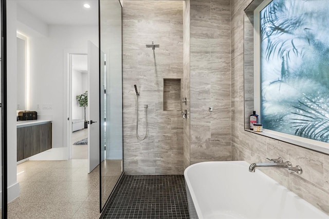 bathroom with a freestanding tub, tile walls, vanity, and a walk in shower