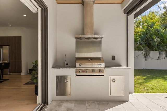 view of patio featuring a sink, an outdoor kitchen, fence, and a grill