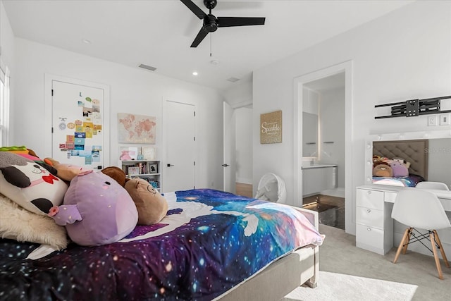 carpeted bedroom with built in study area, a ceiling fan, visible vents, and connected bathroom