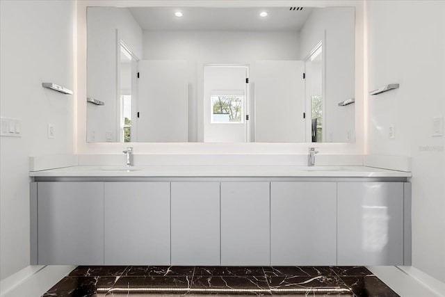 full bathroom with double vanity, recessed lighting, and a sink