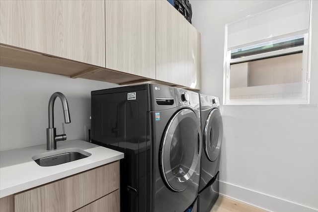 laundry room with a sink, cabinet space, and washer and dryer