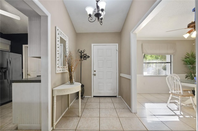 foyer featuring light tile patterned floors, ceiling fan with notable chandelier, and baseboards