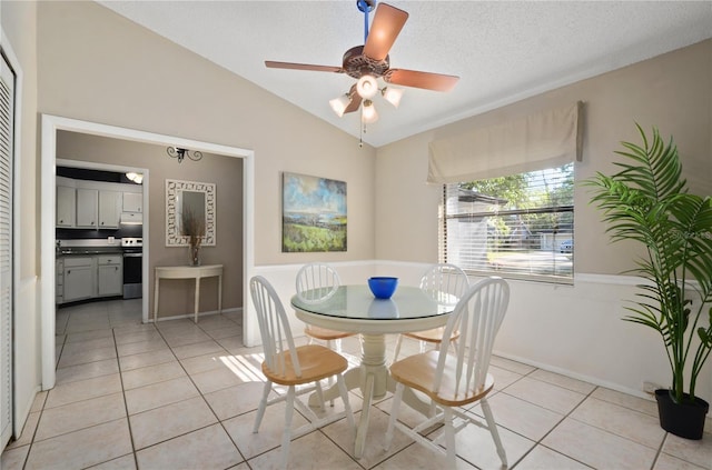 dining room with a textured ceiling, lofted ceiling, light tile patterned floors, and ceiling fan