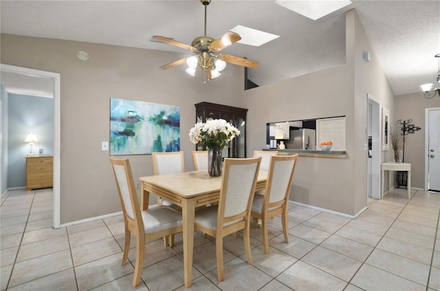 dining area featuring light tile patterned floors, a ceiling fan, baseboards, a textured ceiling, and lofted ceiling with skylight