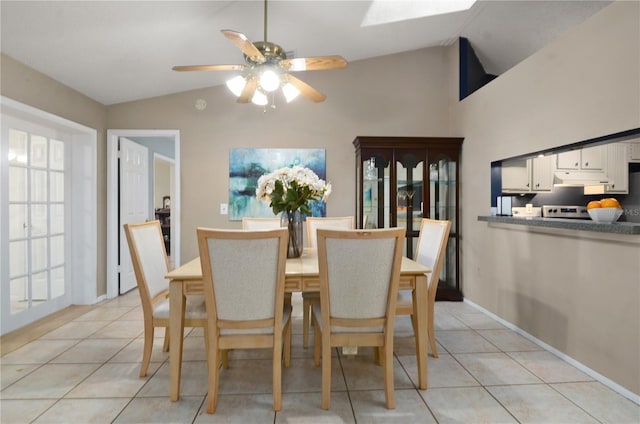 dining area with lofted ceiling with skylight, light tile patterned floors, and a ceiling fan