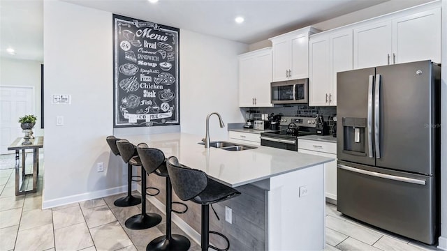 kitchen with a sink, tasteful backsplash, appliances with stainless steel finishes, a breakfast bar area, and white cabinets