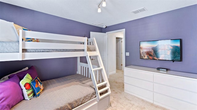 carpeted bedroom with visible vents and rail lighting