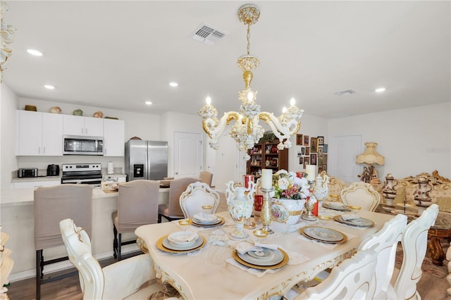 dining room with wood finished floors, a notable chandelier, recessed lighting, and visible vents