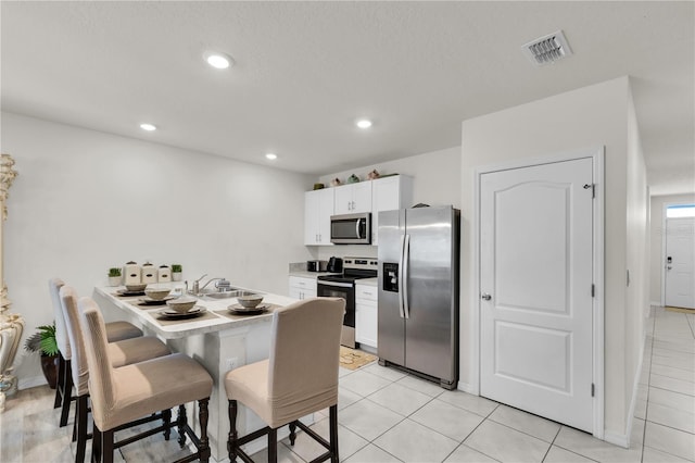 kitchen with a breakfast bar, recessed lighting, a sink, white cabinets, and appliances with stainless steel finishes