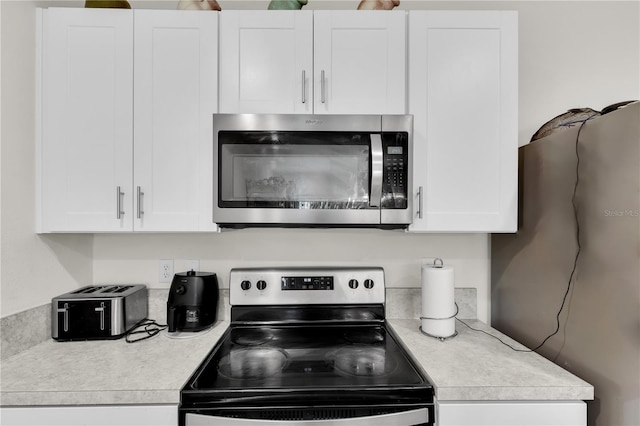 kitchen with appliances with stainless steel finishes, white cabinets, and light countertops