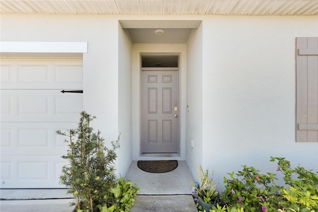 property entrance featuring a garage and stucco siding