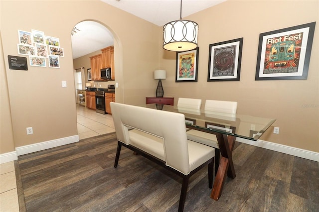 dining space featuring baseboards, arched walkways, and wood finished floors