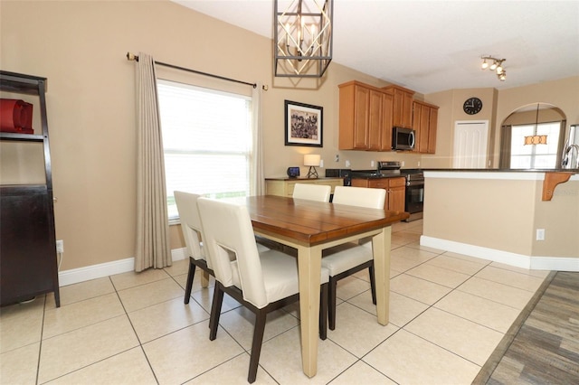 dining area with light tile patterned flooring, a chandelier, and baseboards