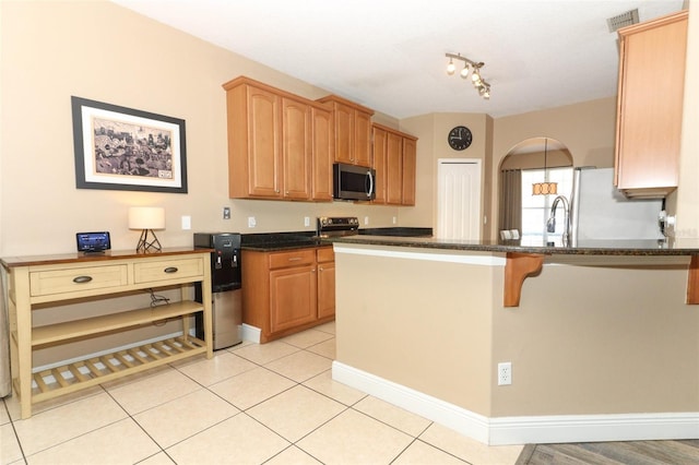 kitchen featuring visible vents, light tile patterned floors, appliances with stainless steel finishes, a kitchen breakfast bar, and a peninsula