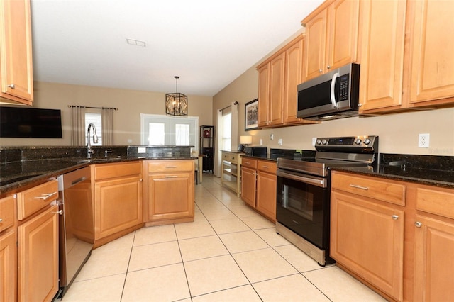 kitchen featuring a wealth of natural light, dark stone counters, appliances with stainless steel finishes, and light tile patterned floors