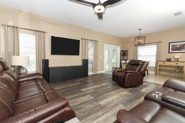 living area featuring visible vents, baseboards, ceiling fan with notable chandelier, french doors, and wood finished floors