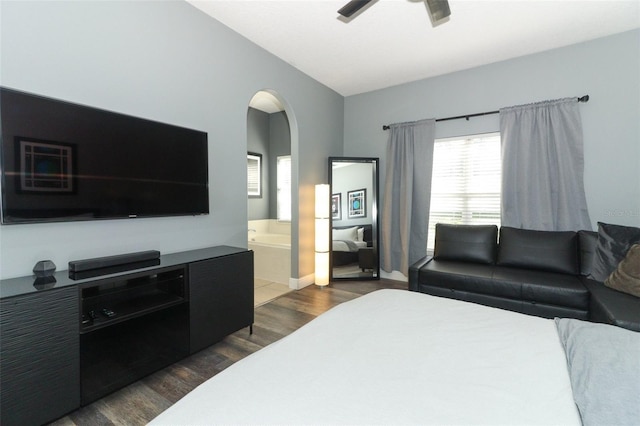 bedroom with a ceiling fan, connected bathroom, arched walkways, baseboards, and dark wood-style flooring