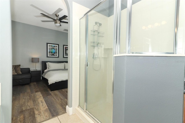 full bathroom featuring a shower stall, wood finished floors, a ceiling fan, and ensuite bathroom