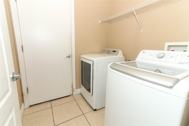 washroom with light tile patterned floors, separate washer and dryer, and laundry area