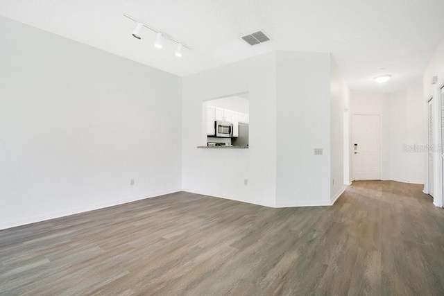 unfurnished living room featuring visible vents, baseboards, and wood finished floors