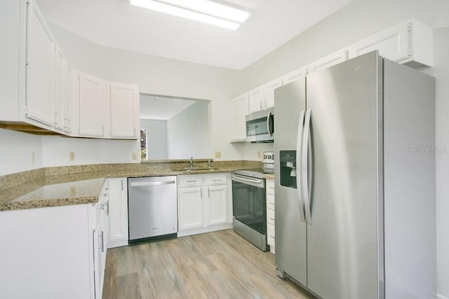 kitchen with white cabinets, light wood-style floors, appliances with stainless steel finishes, and a sink