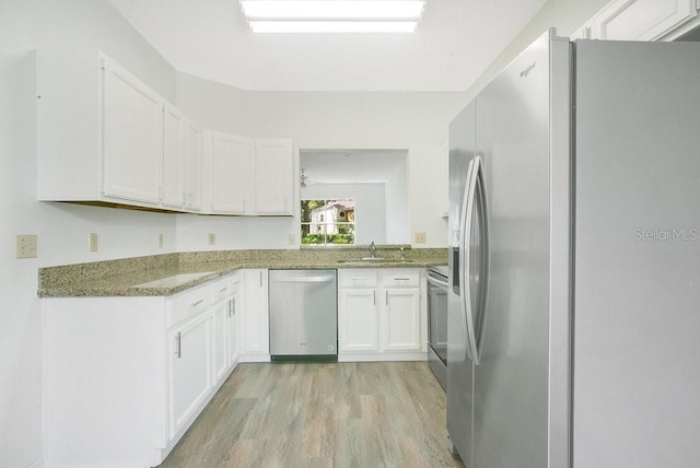 kitchen featuring a sink, white cabinets, light wood finished floors, and stainless steel appliances