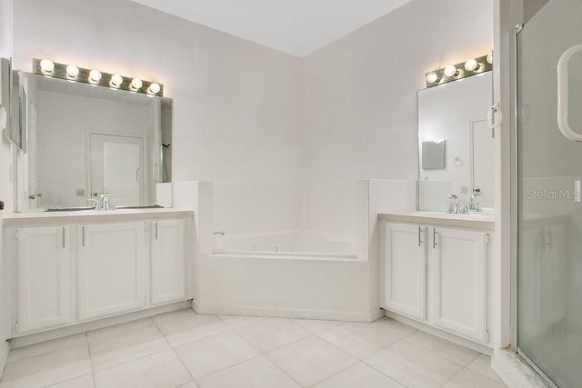 bathroom featuring tile patterned flooring, a garden tub, two vanities, and a sink