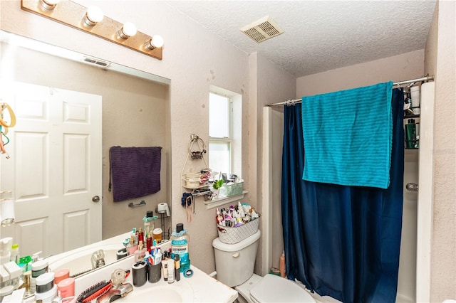 full bathroom with visible vents, toilet, a textured ceiling, and vanity