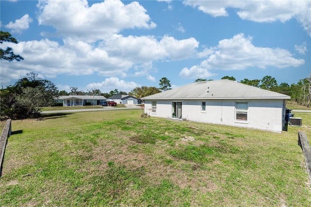 back of property with central air condition unit and a yard