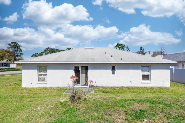 back of property with a lawn and concrete block siding