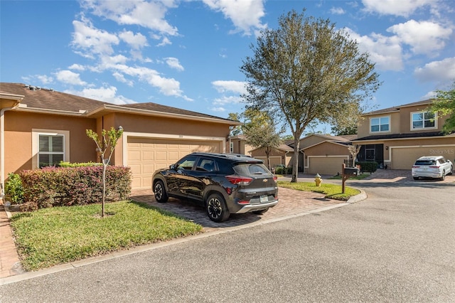 view of front of property with stucco siding, driveway, a residential view, and an attached garage