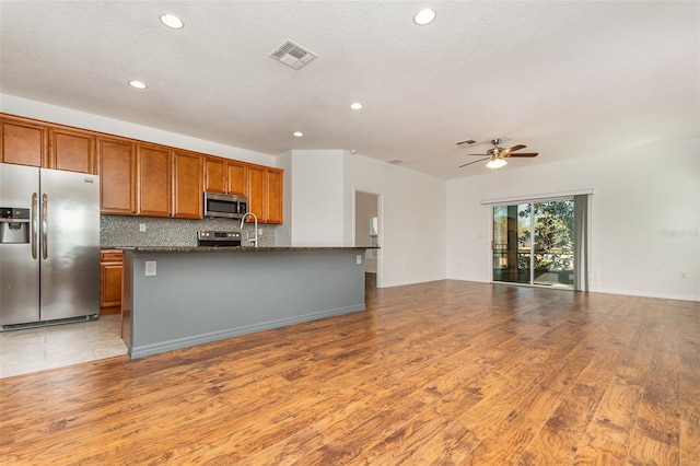 kitchen with visible vents, open floor plan, appliances with stainless steel finishes, decorative backsplash, and ceiling fan