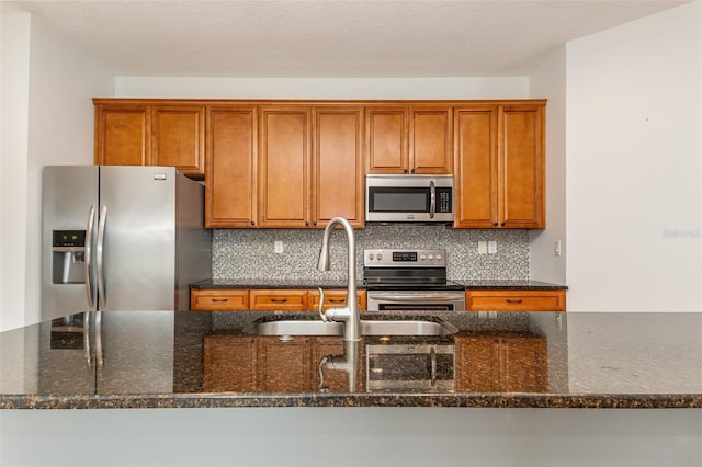 kitchen featuring tasteful backsplash, brown cabinets, appliances with stainless steel finishes, and a sink