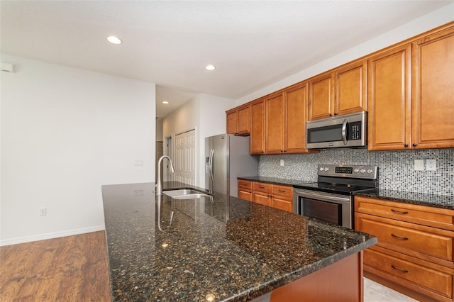 kitchen featuring a sink, backsplash, appliances with stainless steel finishes, and brown cabinetry