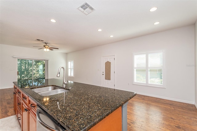 kitchen featuring brown cabinetry, visible vents, light wood-style floors, and a sink