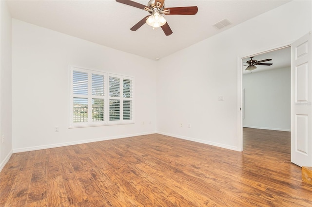 spare room with ceiling fan, visible vents, baseboards, and wood finished floors