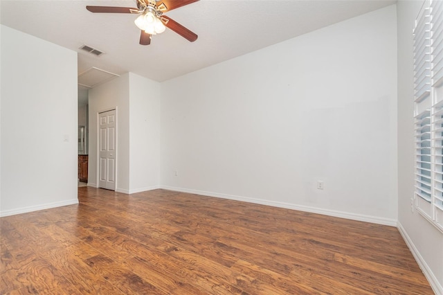 unfurnished room with wood finished floors, a ceiling fan, visible vents, and baseboards