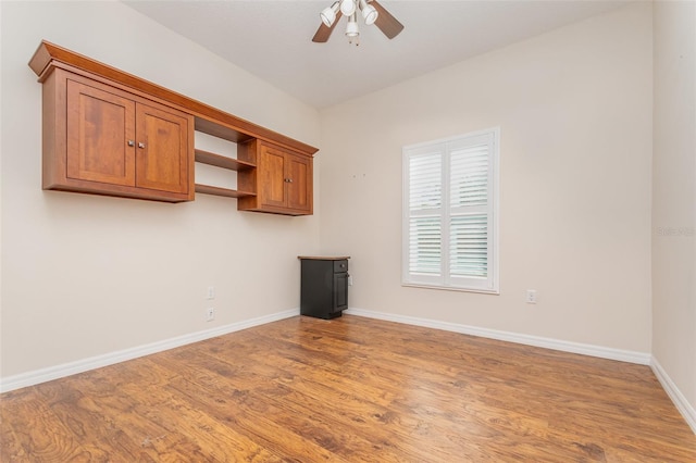 unfurnished room with baseboards, wood finished floors, and a ceiling fan