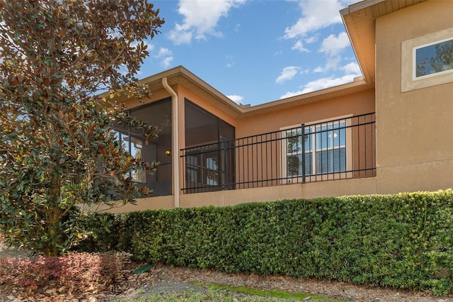 view of property exterior with a sunroom and stucco siding