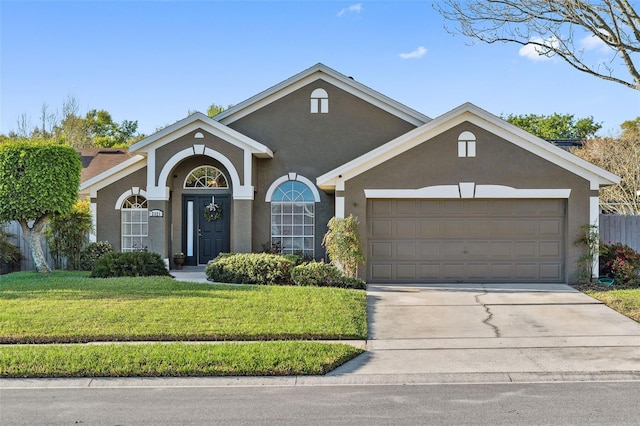 view of front of property featuring stucco siding, driveway, a front yard, and a garage