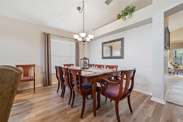 dining room featuring baseboards, visible vents, light wood finished floors, and a chandelier