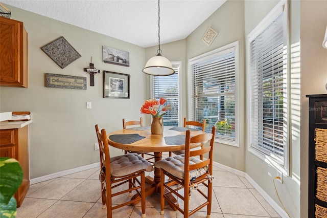 dining space featuring light tile patterned flooring, a textured ceiling, and baseboards