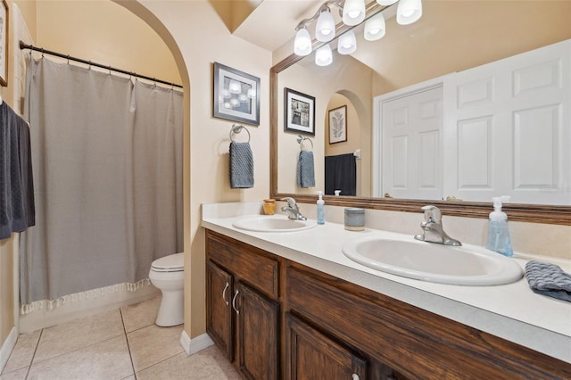 bathroom featuring a sink, toilet, double vanity, and tile patterned floors