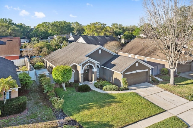 view of front of home with fence, a front yard, stucco siding, a garage, and driveway