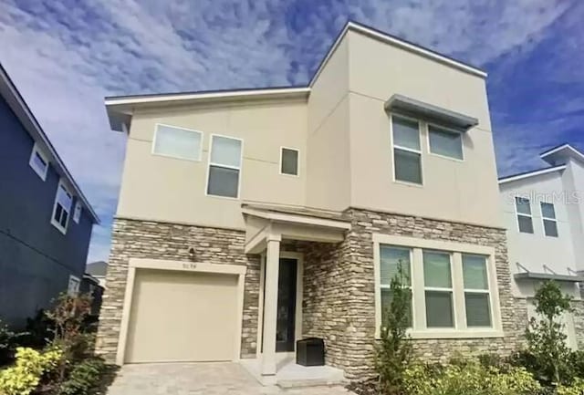 view of front of house featuring stucco siding, stone siding, a garage, and driveway